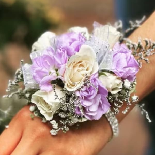 Wrist corsage with lavender and white roses on a hand