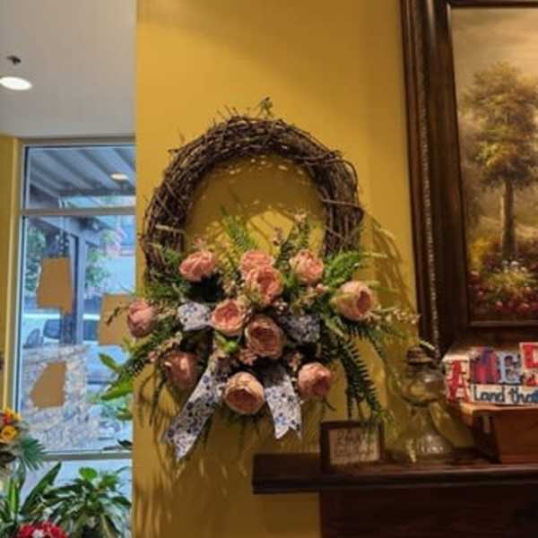 Pink rose arrangement on a grapevine wreath with a ribbon bow