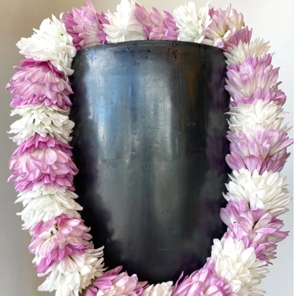 Pink and white flower lei draped over a black mannequin bust