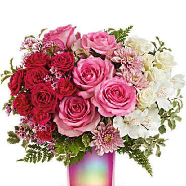 Pink and red roses with white flowers in a pink glass vase
