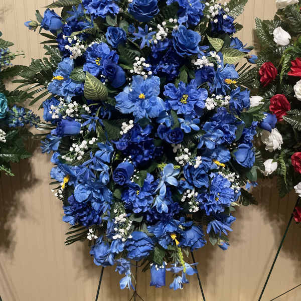 Large blue floral standing spray with mixed blooms and greenery