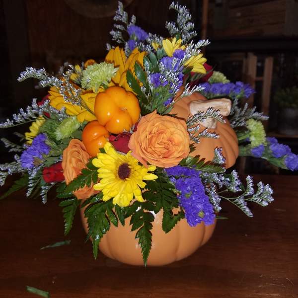 Fall floral arrangement in a pumpkin container with sunflowers and roses