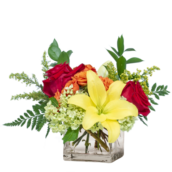 Bouquet of red roses, yellow lilies, and orange flowers in a clear glass vase