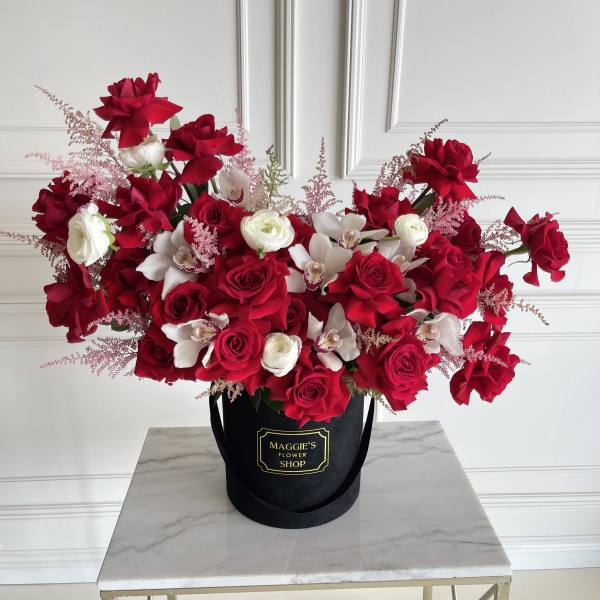 Red and white roses with orchids in a black hatbox