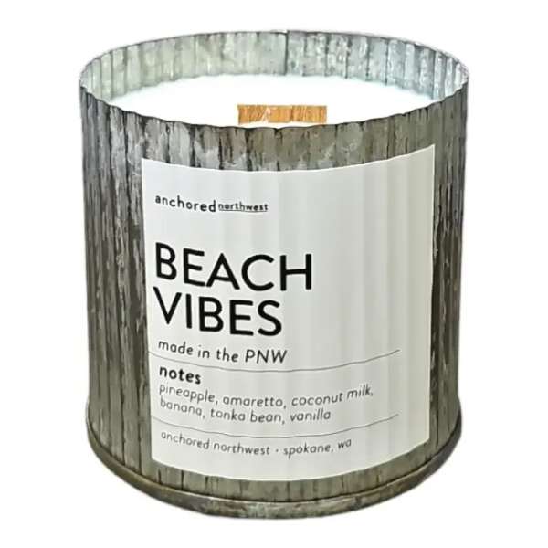 A scented candle in a metal tin labeled Beach Vibes