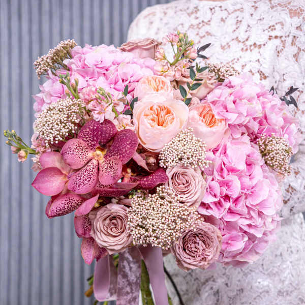 Bride holding a pink bouquet with roses, hydrangeas, and orchids