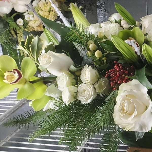 Long white floral arrangement with green orchids and roses