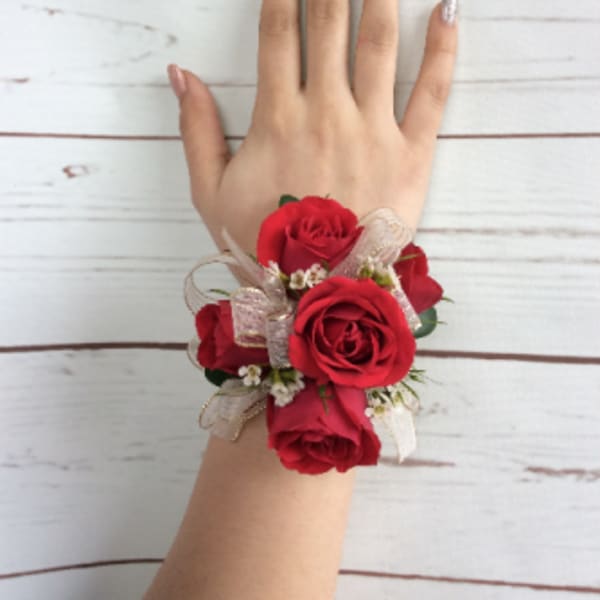 Red rose wrist corsage with ribbon on a hand