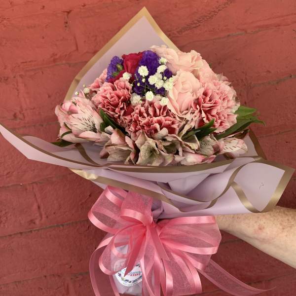 Pink and purple mixed bouquet wrapped in paper with a pink ribbon
