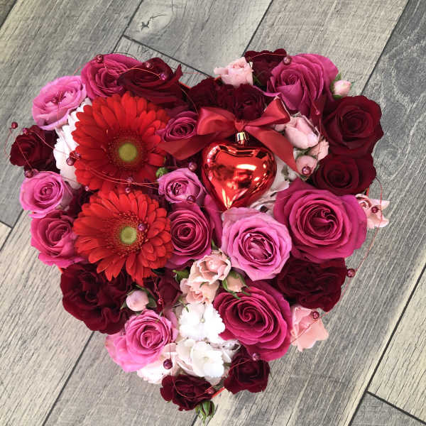 Heart-shaped bouquet of pink and red roses with two red gerbera daisies