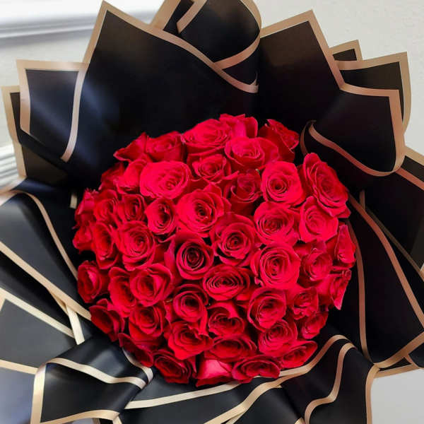 Bouquet of red roses wrapped in black paper with gold trim