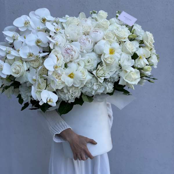 Large white bouquet with orchids and roses in a white box