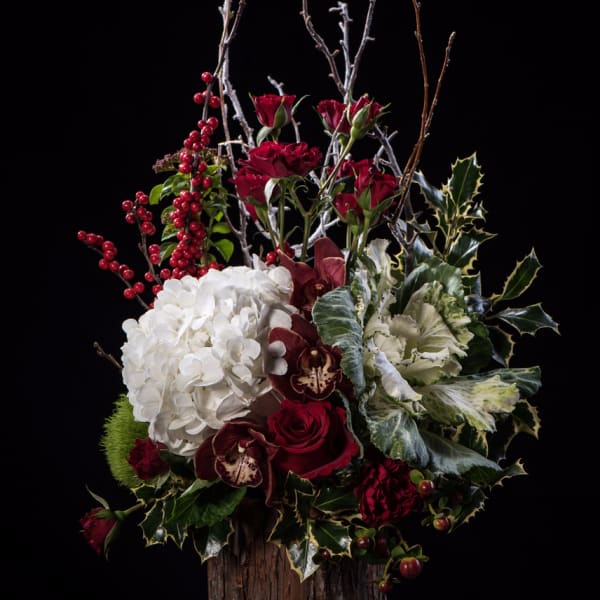 Red roses, white hydrangea, and orchids in a rustic wood vase