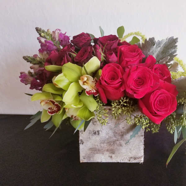 Pink roses and green orchids in a rustic square container