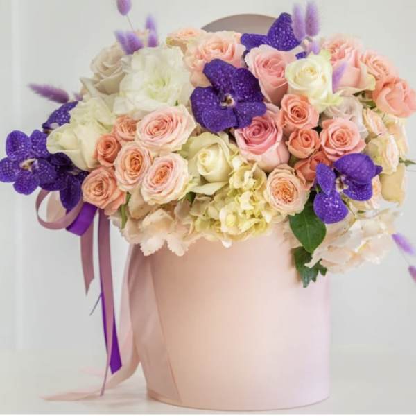 Pink and cream roses with purple orchids in a blush hatbox