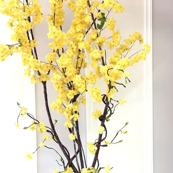 Tall yellow flowering tree arrangement in a moss-covered base