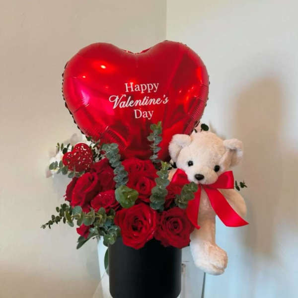 Red rose arrangement with a heart balloon and teddy bear in a black box