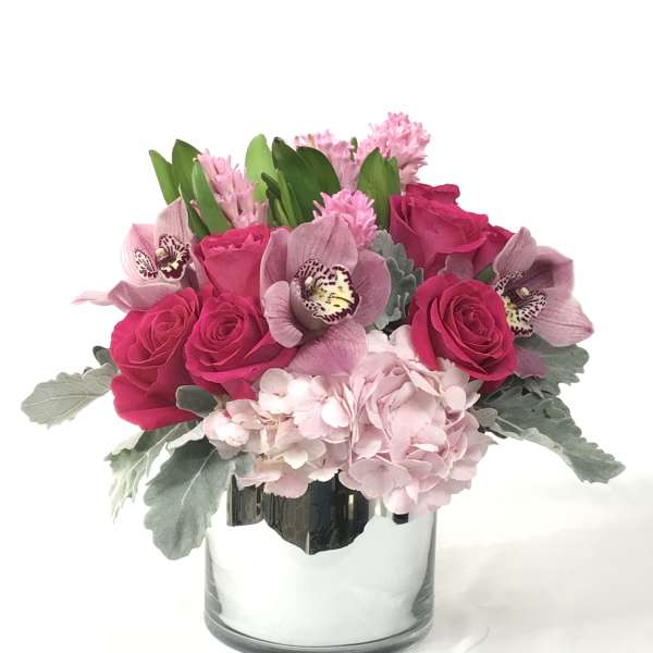 Pink roses and orchids arranged in a clear glass vase