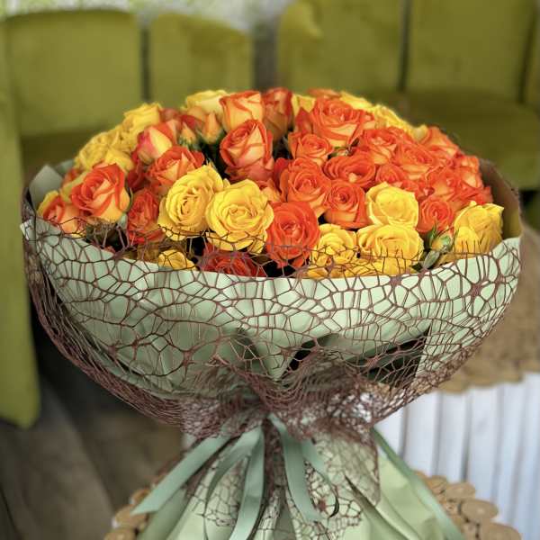 Bouquet of orange and yellow roses wrapped in green paper