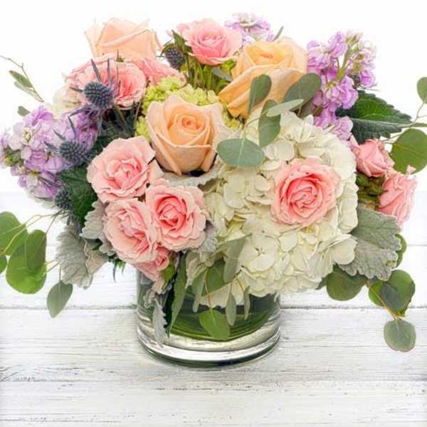 Pastel roses and hydrangeas arranged in a clear glass vase