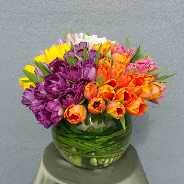 Colorful tulip bouquet in a round glass vase
