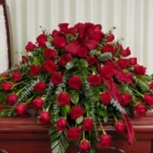 Large red rose casket spray on a wooden casket