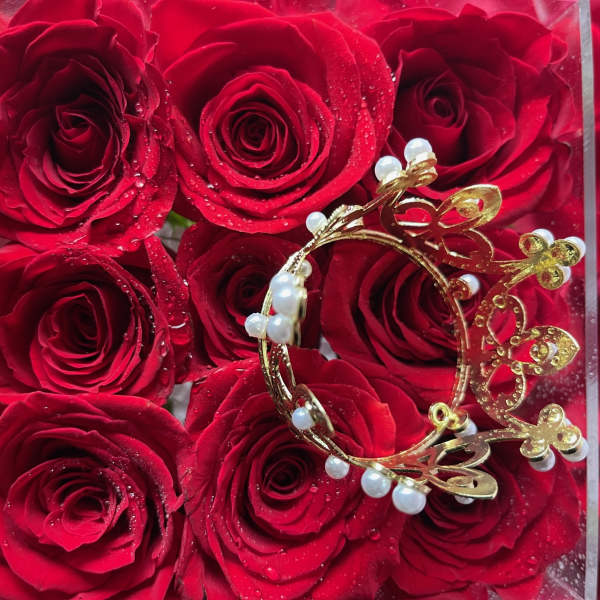 Red roses in a clear box with a gold butterfly ornament