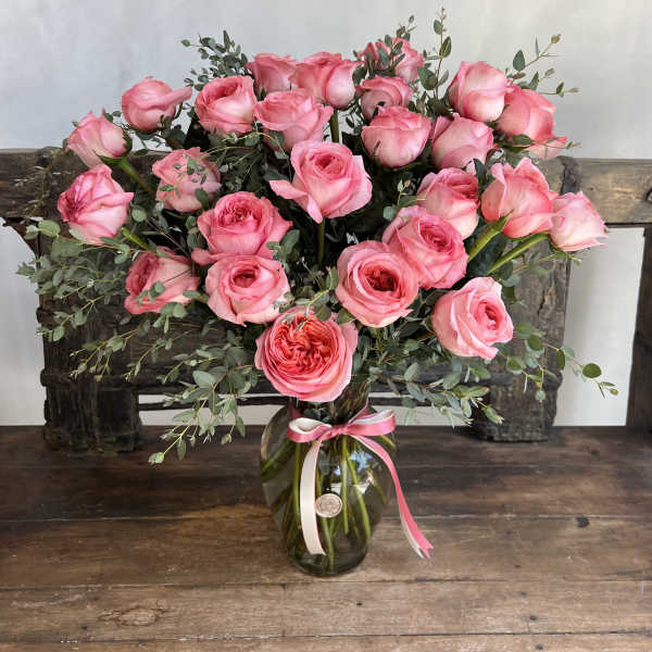 Pink roses arranged in a glass vase with a ribbon