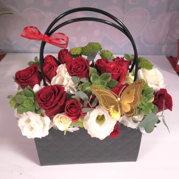 Red and white roses in a black handled basket with a butterfly decoration