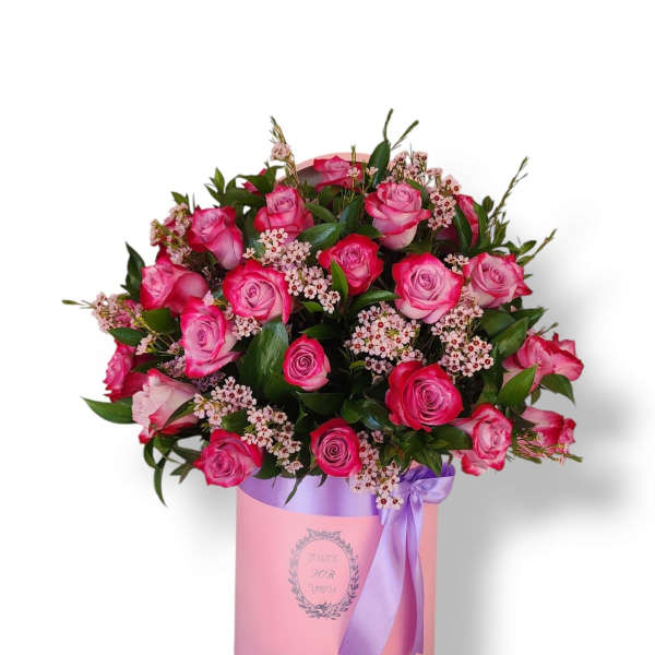 Pink roses arranged in a round box with a purple ribbon