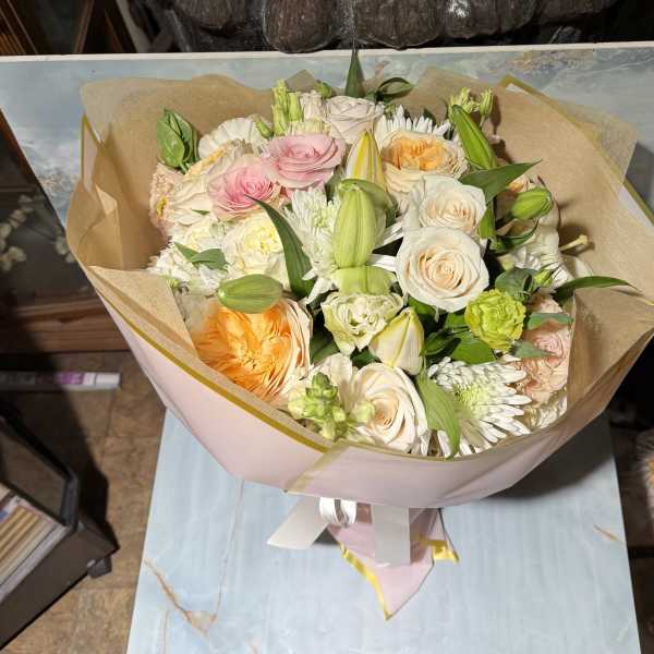 Bouquet of pink, white, and peach flowers wrapped in tan paper