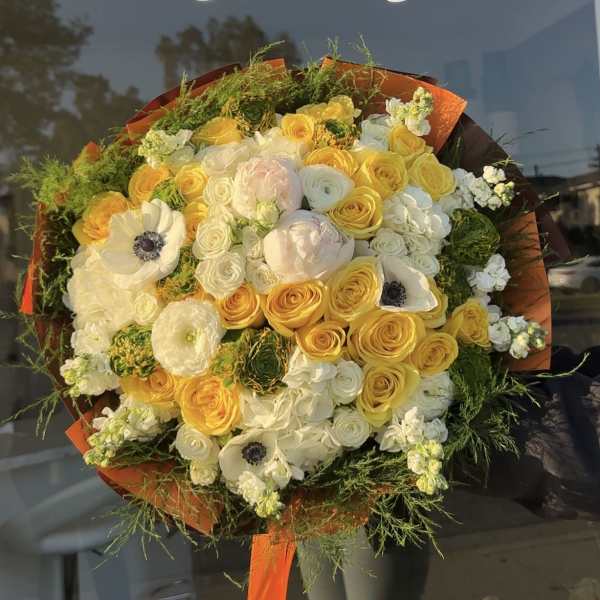 Large bouquet of yellow and white flowers wrapped in orange paper