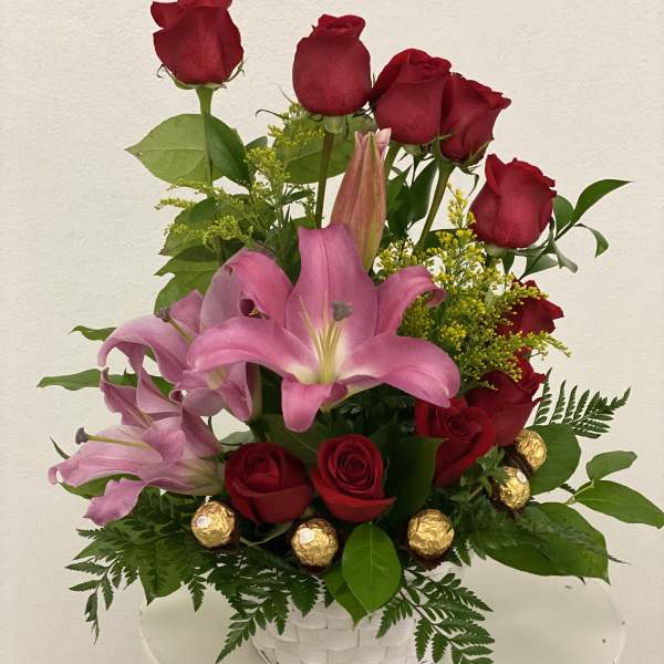 Red roses and pink lilies in a white basket with gold chocolates