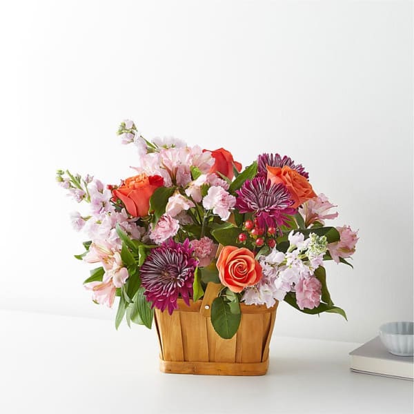Mixed bouquet in a wooden basket with pink and orange flowers