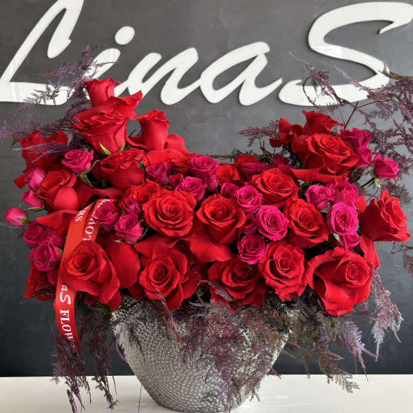 Large arrangement of red and pink roses in a silver vase