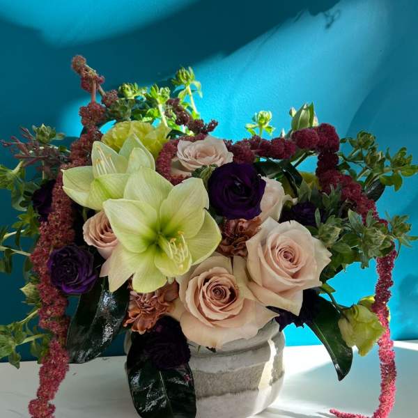 Arrangement of pale roses and green lilies in a white vase
