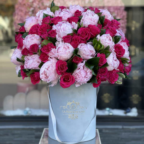 Pink peonies and hot pink roses in a white hatbox