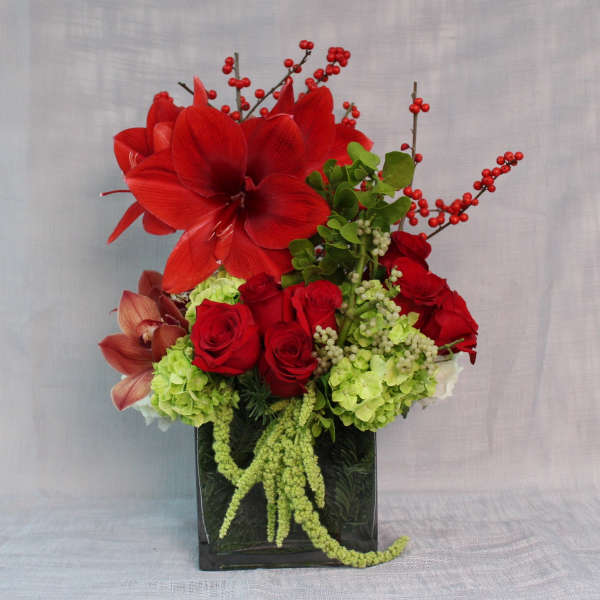 Red amaryllis and roses in a black vase with green hydrangeas