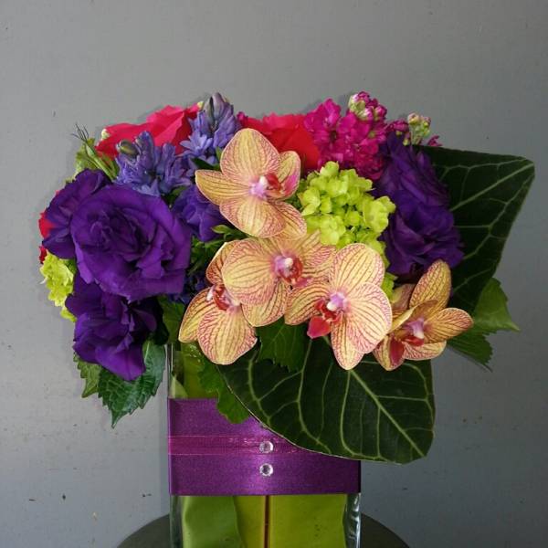 Colorful bouquet with orchids and purple flowers in a glass vase