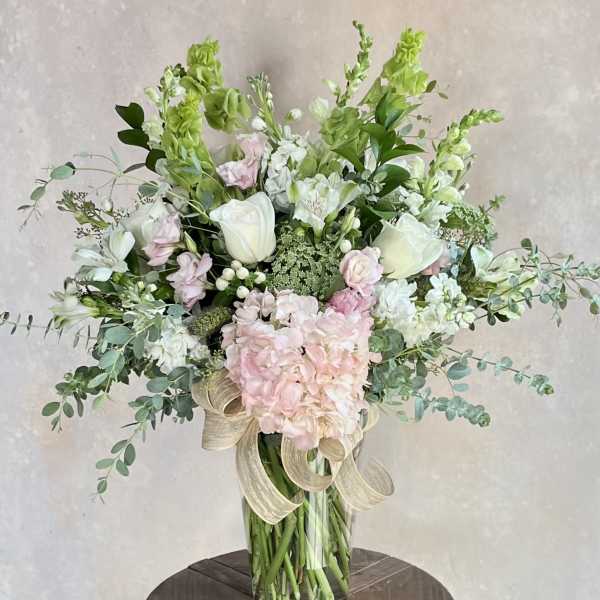 Tall bouquet of white and pale pink flowers in a glass vase
