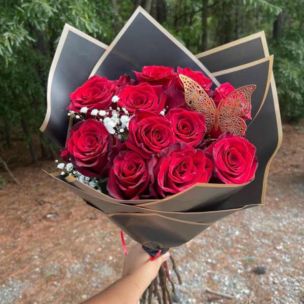 Bouquet of red roses wrapped in black paper with a butterfly accent