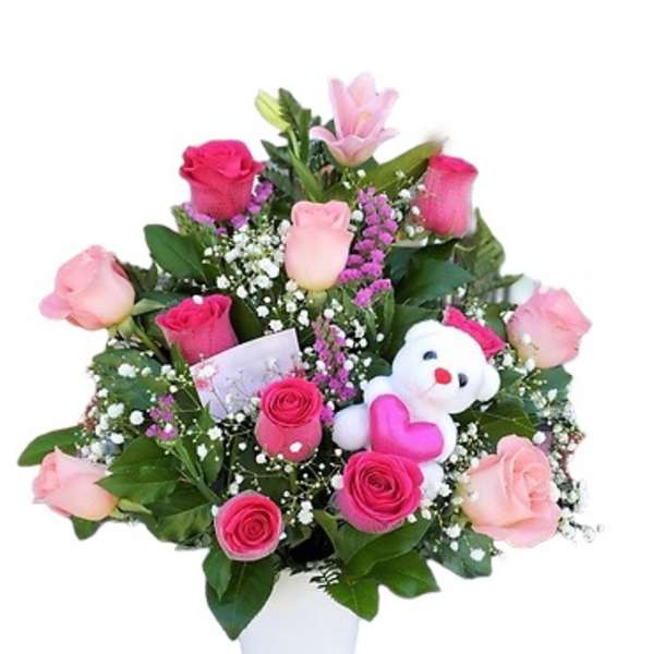 Pink rose bouquet in a white vase with a small teddy bear