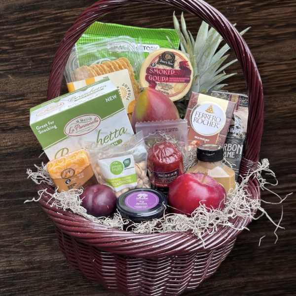 Gift basket with snacks, cheese, fruit, and chocolates