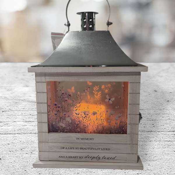 Memorial lantern with a glowing floral scene and sympathy text