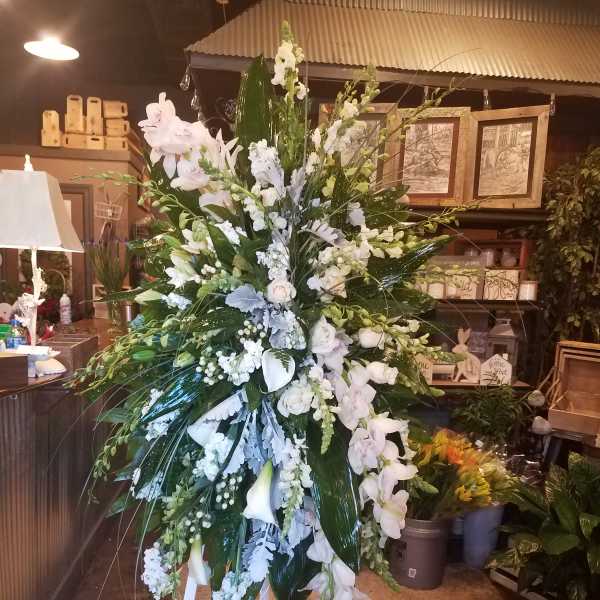 Tall white floral standing spray on a white easel