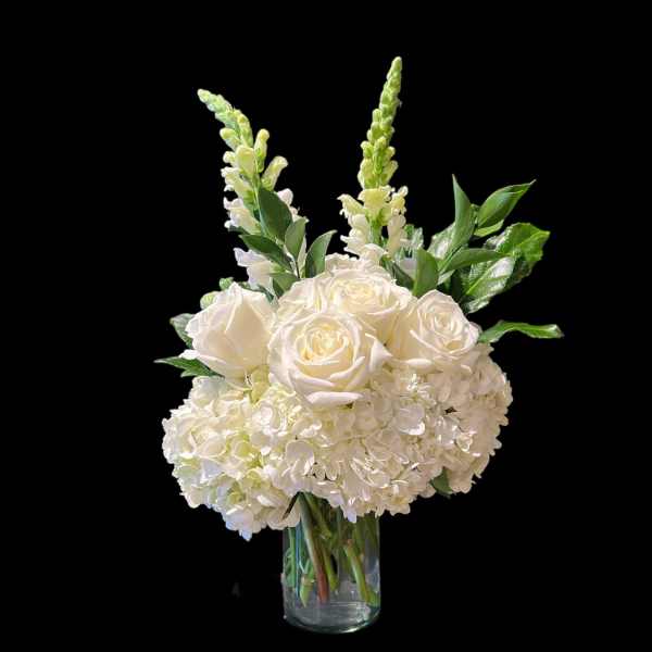 White roses and hydrangeas in a clear glass vase