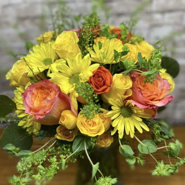 Bouquet of yellow daisies and orange-pink roses in a dark vase