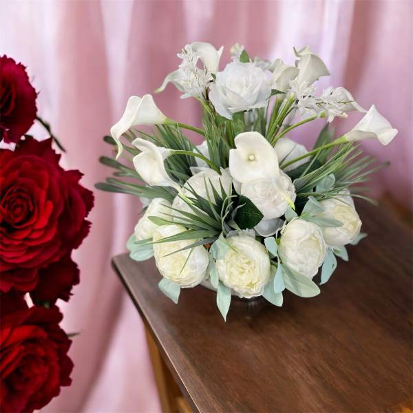 White floral bouquet with calla lilies and roses on a table