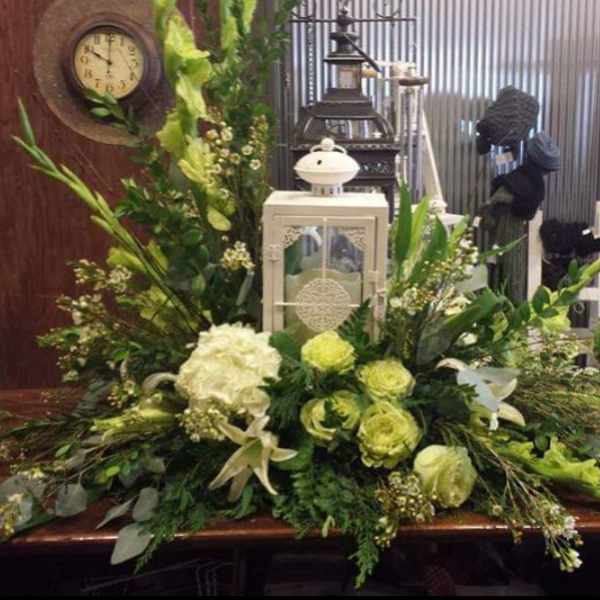 Large green and white floral arrangement with a lantern centerpiece