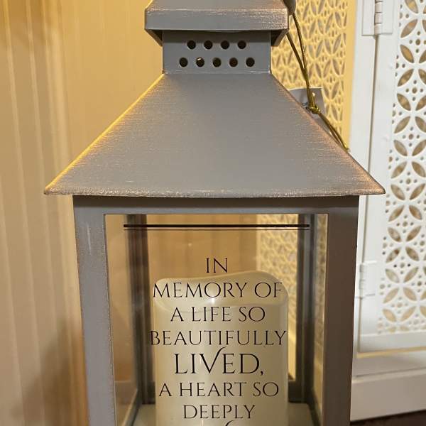 Gray memorial lantern with a candle and sympathy message